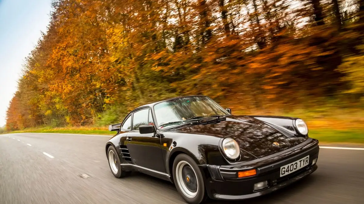 Svart Porsche 911 Turbo på en höstväg